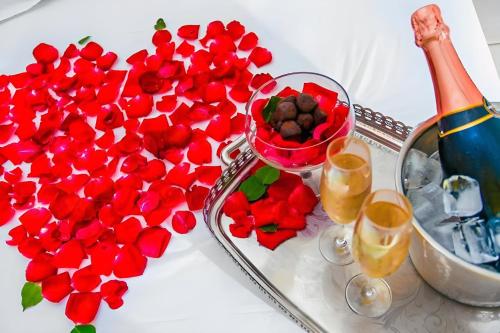 a table with red flowers and a bottle of champagne at Villa Baobá Pousada & Spa in Búzios