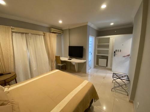 a bedroom with a bed and a desk and a television at Anacã São Carlos in São Carlos