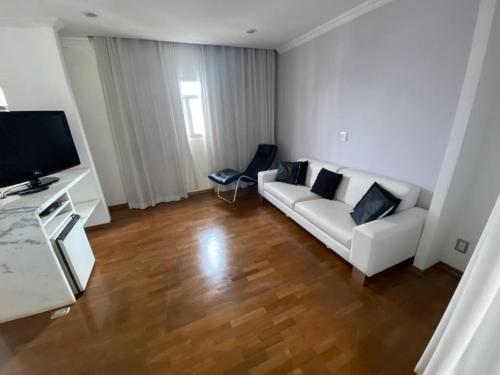 a living room with a white couch and a television at Anacã São Carlos in São Carlos