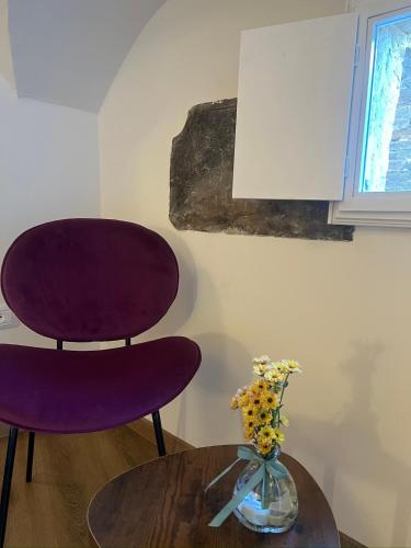 a purple chair and a table with a vase of flowers at Palazzo Cagianelli in Perugia