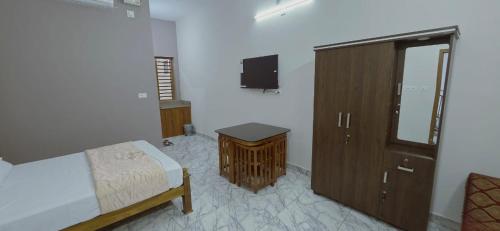 a bedroom with a bed and a cabinet and a tv at Alanchery Residency in Cheruthuruthi