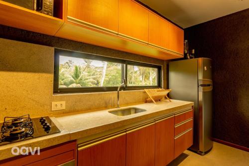 eine Küche mit einer Spüle, einem Kühlschrank und einem Fenster in der Unterkunft Villa Kamby na Rota Ecológica dos Milagres by Qavi in São Miguel dos Milagres