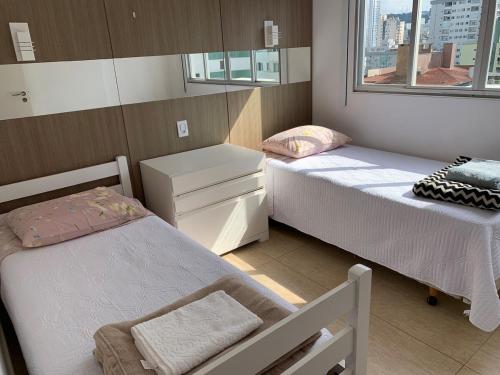 a small room with two beds and a window at Apartamento fantástico com linda vista lateral do mar in Balneário Camboriú
