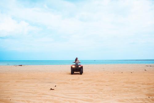 a person riding a quad bike on the beach at Bangalô Suíte Sol do Gostoso in São Miguel do Gostoso