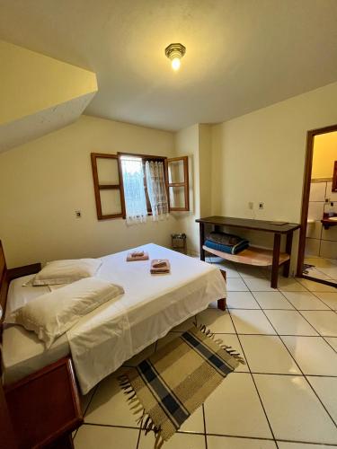 a bedroom with a bed and a desk in it at Pousada Murmúrio das Águas in São Francisco Xavier