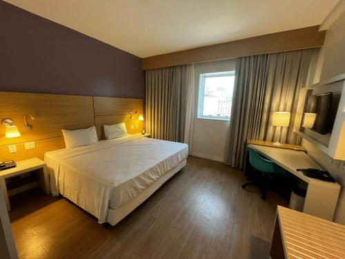 a hotel room with a bed and a desk at Stay Inn Santos Sua acomodação com cara de Hotel in Santos