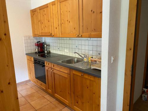 Una cocina con gabinetes de madera y un fregadero. en Spacious and comfortable, en Val dʼIlliez