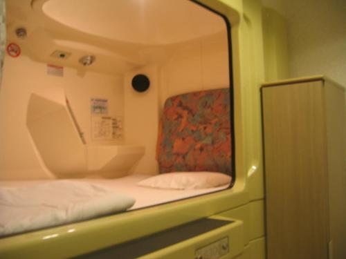 reflejo de una cama y una silla en un espejo en Capsule&Spa Grand Sauna Shinsaibashi, en Osaka