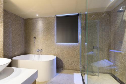 a bathroom with a tub and a glass shower at Inhouse Hotel Taichung in Taichung