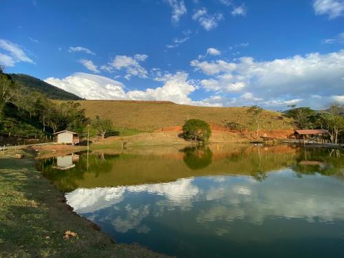 a body of water with a hill in the background at Fazenda - Lago in São José dos Campos