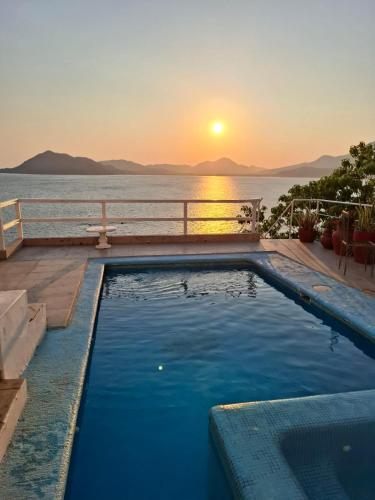 a swimming pool with a sunset in the background at Casa Tortugas Manzanillo in Manzanillo