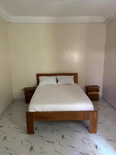 a bedroom with a bed with white sheets and two night stands at Immeuble Houleye Moctar Sow in Dakar