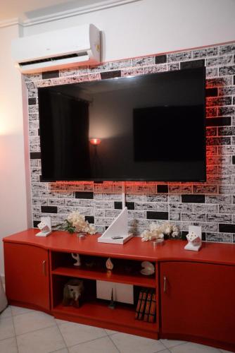 a television on a brick wall with a red cabinet at Pantelia LuxMax Experience in Loutraki