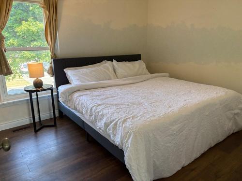 a bedroom with a bed with a white comforter and a window at Royal Rays in Bowmanville