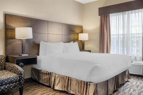 a hotel room with a large bed and a chair at Best Western Plus Bridgewater Hotel & Convention Centre in Bridgewater