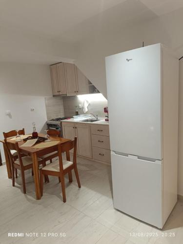 una cucina con un tavolo e un frigorifero bianco di Ξενώνας "Alexandra's Coffee House" a Volímai