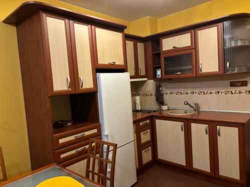 une cuisine avec des armoires en bois et un réfrigérateur blanc dans l'établissement Galina apartment, à Ruse
