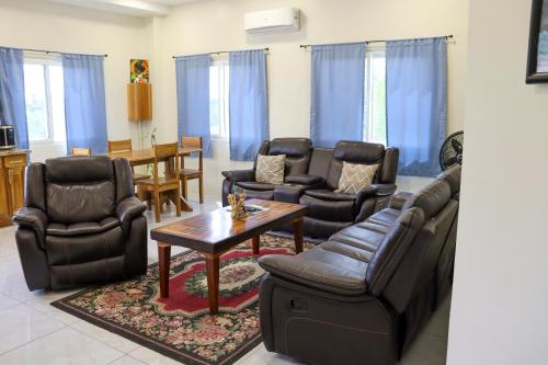 a living room with leather furniture and a table at Harbour Place Suites in Placencia Village
