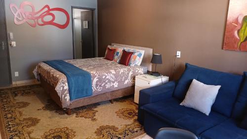 a bedroom with a bed and a blue couch at Studio Barreto Leme Ap72 in Campinas