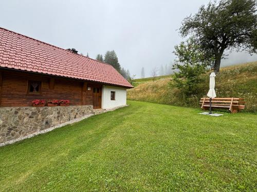 a wooden cabin with a grass yard next to a building at Grunt Sonek in Mislinja