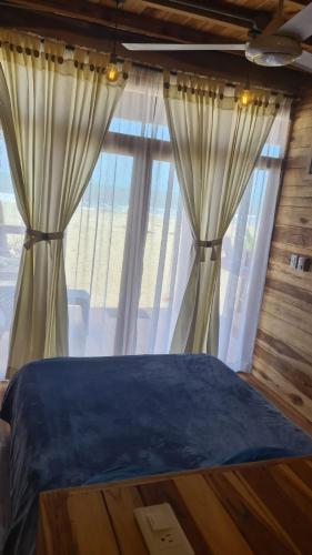 a bedroom with a bed and a large window at Casa Maya Mendihuaca in Playa Mendiguaca