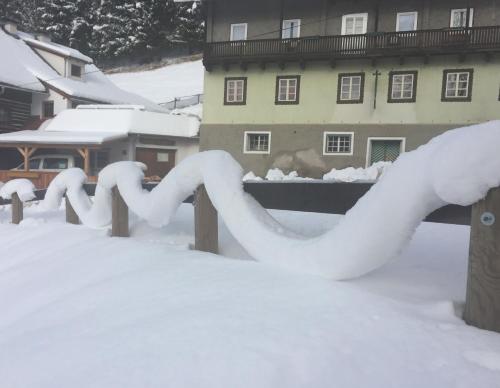 a fence covered in snow in front of a building at Gasthaus Luggwirt in Gnesau