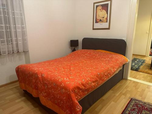 a bed with an orange comforter in a room at Goetheanum Casa in Dornach