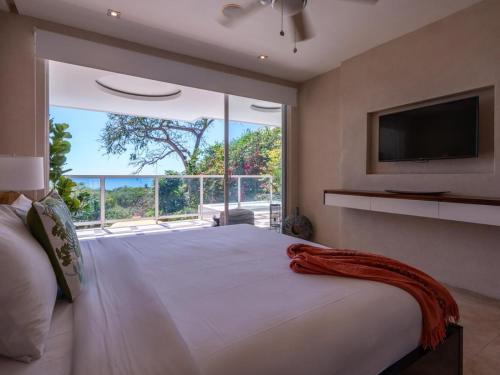 a bedroom with a large bed with a large window at Casa White#2 Beautiful modern beach house in Sámara