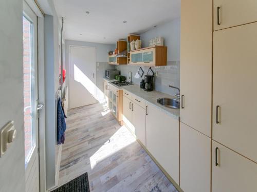 a kitchen with white cabinets and a wooden floor at Comfortable vacation home near the sea in Noordwijkerhout