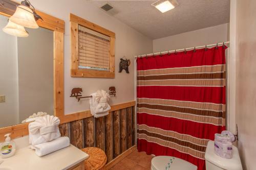 ein Badezimmer mit einem roten Duschvorhang und einem WC in der Unterkunft Bushwood Lodge by American Patriot Getaways in Chalet Village