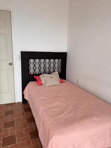 a small bedroom with a bed with a pink blanket at Hotel la barranca 5 in Zacatlán