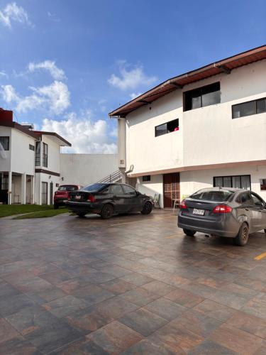 twee auto's geparkeerd op een parkeerplaats voor een gebouw bij Hotel la barranca 5 in Zacatlán