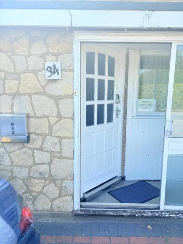 a white door of a house with a stone wall at EasyStay - Bright & Spacious house, recently renovated, Free Parking near Luton Airport in Luton