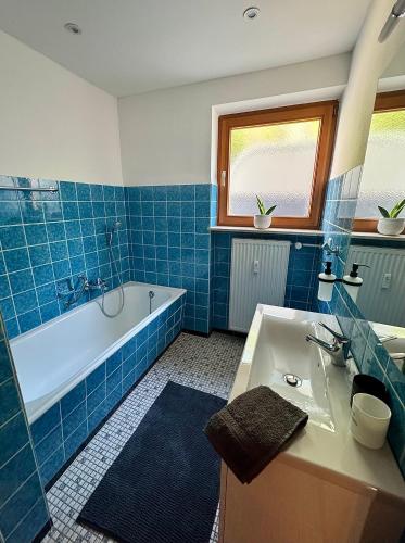 a blue tiled bathroom with a tub and a sink at Landglück in Tettnang