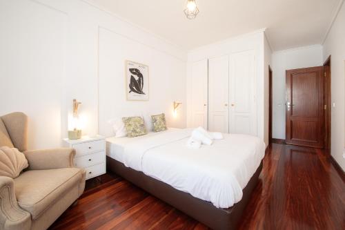 a white bedroom with a bed and a couch at Cozy Traveller Apartment & Garage in Aveiro
