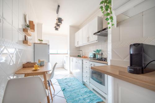 a kitchen with white cabinets and a small table and a counter at Cozy Traveller Apartment & Garage in Aveiro