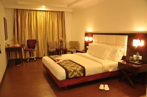 a hotel room with a bed and a desk and chairs at Grand Clarks Inn in Badami