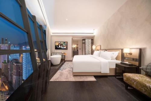 a bedroom with a large white bed and a tub at Chongqing KS Kongshang Hotel in Chongqing
