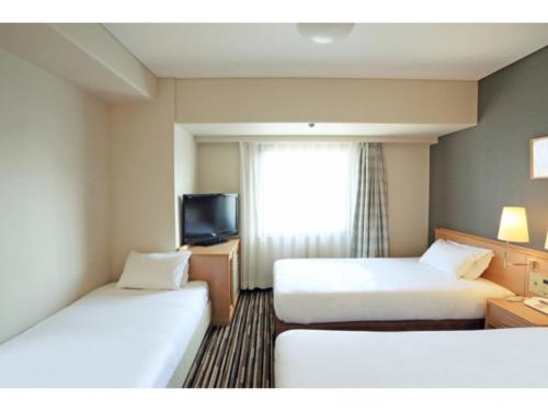 a hotel room with two beds and a television at Smile Hotel Tokushima - Vacation STAY 61139v in Tokushima