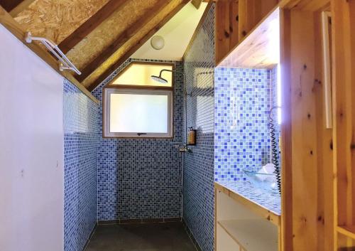 baño con paredes de azulejos azules y ventana en RAIATEA - Fare Ora, en Taoru