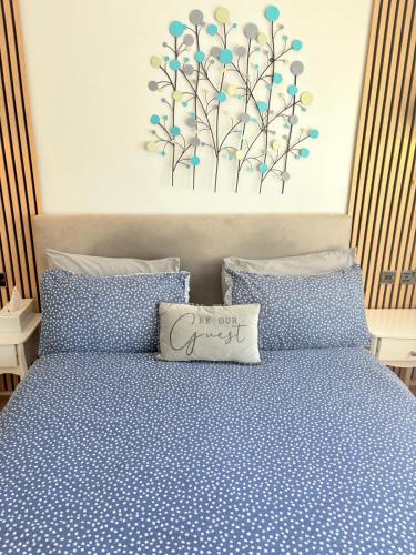 a bed with blue polka dot sheets and a pillow on it at EasyStay - Bright & Spacious house, recently renovated, Free Parking near Luton Airport in Luton