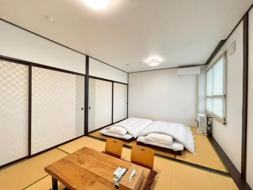 ein Zimmer mit zwei Betten und einem Tisch und Stühlen in der Unterkunft ＳＥＫＫＡ ＳＨＩＲＥＴＯＫＯ - Vacation STAY 66952v in Shimatokkari