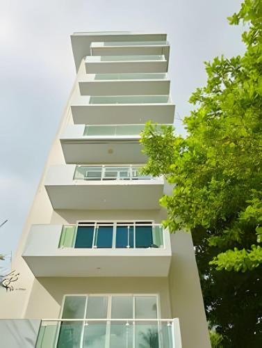 a tall white building with windows and trees at Beachside 1Bdrm Apt. Hidden Oasis with Pool & BBQ in Juan Dolio