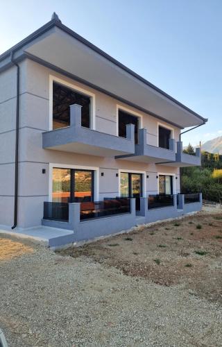 a large white house with a lot of windows at Apelistra Rooms in Himare