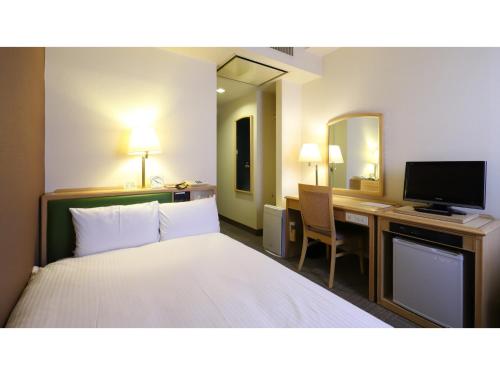 a hotel room with a bed and a desk with a television at Smile Hotel Nagoya Shinkansenguchi - Vacation STAY 77724v in Nagoya
