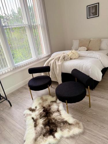 a bedroom with a bed and two chairs and a rug at Edgbaston Retreat-Birmingham City Centre-Double Room in a shared two bedroom apartment in Birmingham