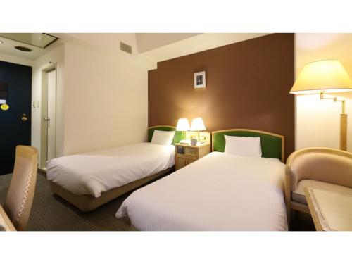 une chambre d'hôtel avec deux lits et une chaise dans l'établissement Smile Hotel Nagoya Shinkansenguchi - Vacation STAY 77734v, à Nagoya