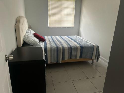 a bedroom with a bed with a striped blanket and a window at Hagat Sunset Retreat in Agat