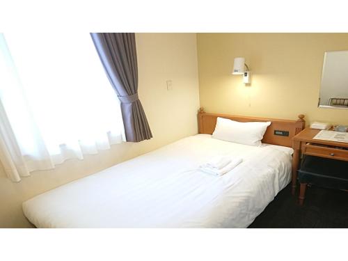 a bedroom with a bed with a desk and a window at Smile Hotel Kobe Motomachi - Vacation STAY 85828v in Kobe