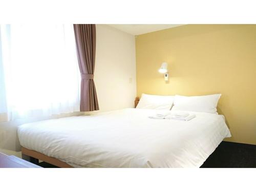 a bedroom with a large white bed with a window at Smile Hotel Kobe Motomachi - Vacation STAY 85850v in Kobe